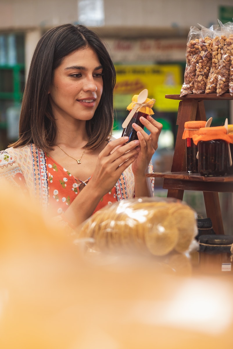 Woman holding a jar of jam while doing grocery shopping