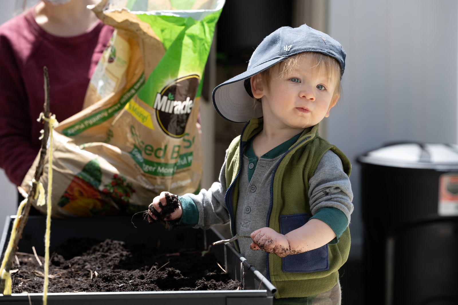 A young boy gardening with mud in his hands