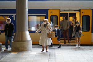 Elderly woman stepping out of a train, wearing a mask