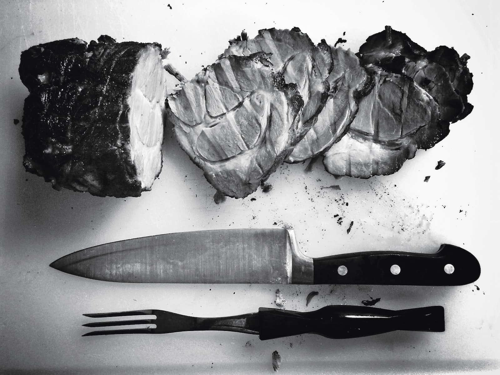 Black and white photo of a sliced piece of meat with cutlery next to it