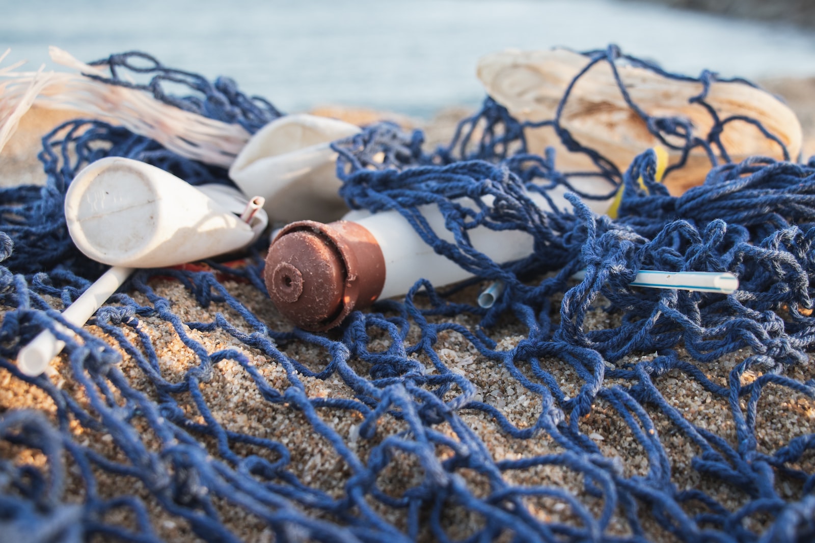 Lots of plastic packagings and trash in a fishnet on a beach