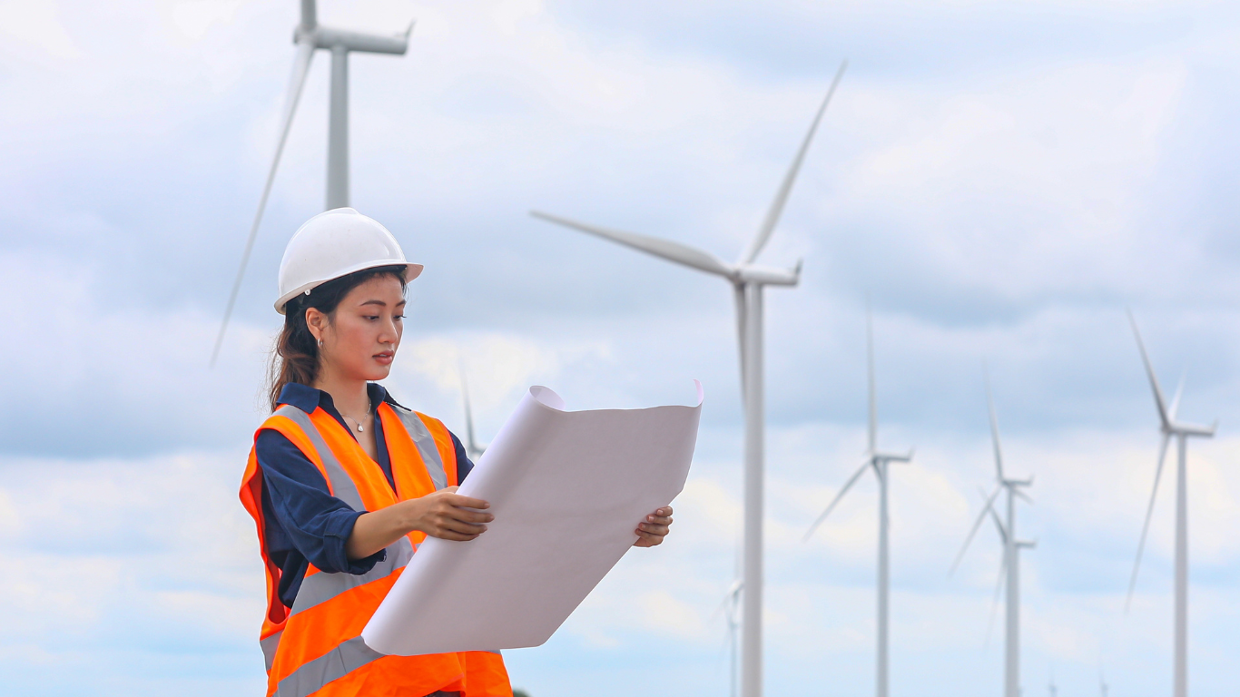 Woman standing in front of wind turbines holding construction plan