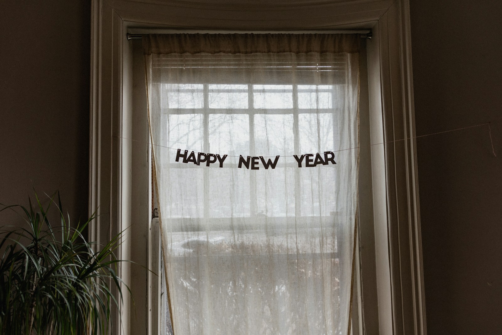 white window curtain during daytime with "Happy New Year" garlaind