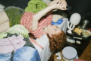 woman laying on a messy bed while shopping online