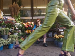 woman sitting in front of a flower shop. movement is happening in front of her